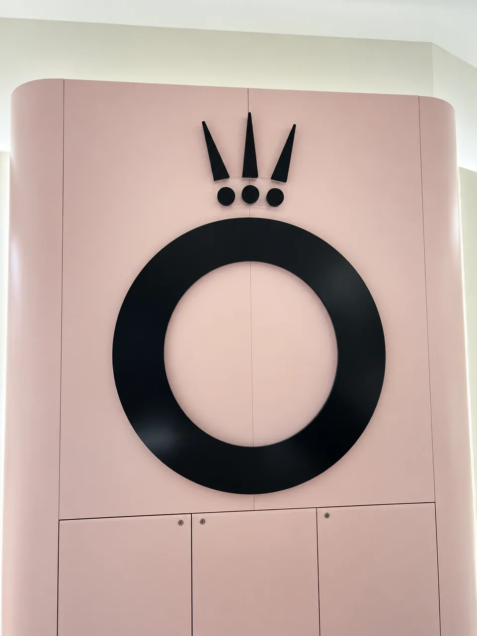 Black raised crown and circular logo on a pink interior wall